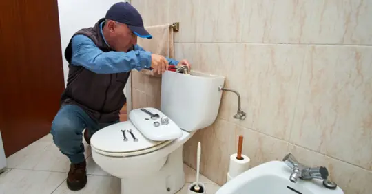 Plumber repairing toilet